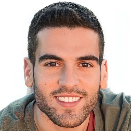 Smiling young man with short dark hair, light beard, and a green jacket looking at the camera.